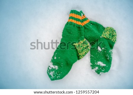 Green knitted socks lying on the snow in winter