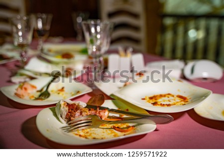 Dishes and glasses are dirty on the table after eating. Empty plates with remnants of food after diner.