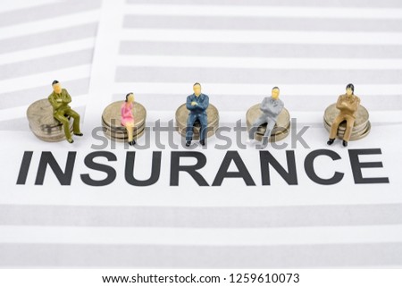 The concept of corporate health insurance from the employer. People figurines sit on piles of coins and on insurance contracts.