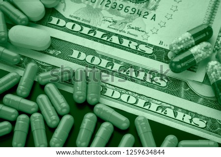 Pharmacy business. Pills on dollar bills toned in green. Concept of choosing an unhealthy lifestyle