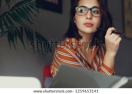 Businesswoman wear glasses in office, work on laptop and think about new ideas with pen. Girl using laptop for work, copy space