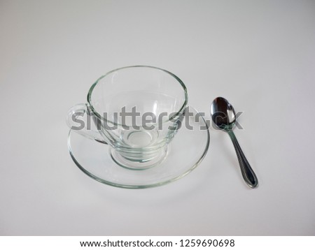 Empty glass of tea with spoon placed on the floor.