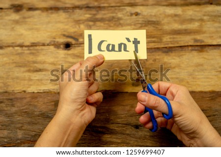 Woman hands holding card with written text i can't do it cutting the letter T with scissors so you read I can in Success and Challenge concept Believe in yourself and Motivation to achieve results. Royalty-Free Stock Photo #1259699407