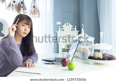 Happy asian beautiful woman working on a laptop sitting on the table  in the house.Morning she dress sweater and work at home .