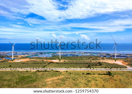 Aerial view of  wind turbines beside sea and coastal road near shrimp farm on a sunny day, Phuoc Dinh, Phan Rang, Ninh Thuan, Vietnam. Mui Dinh lighthouse 3 km away from here