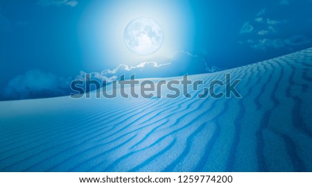 Night sky with blue moon in the clouds with desert (sand dune)"Elements of this image furnished by NASA 