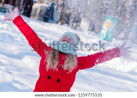 Blurred photo. Cheerful girl throws snow up. Beautiful New Year and Christmas scene. Portrait of the happy child in the winter. Winter holidays concept. 