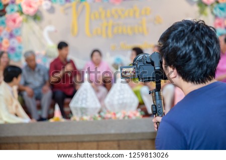 Camera man use steadicam with DSLR camera for video production are shooting movie in wedding ceremony. stabilize tool. stabilizer control machine. movie technology. image for background