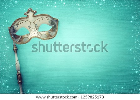 carnival party celebration concept with elegant gold mask on stick over mint wooden background. Top view