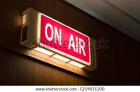 On Air sign icon glowing on the wooden wall of sound recording studios, live broadcast radio production room Royalty-Free Stock Photo #1259831200