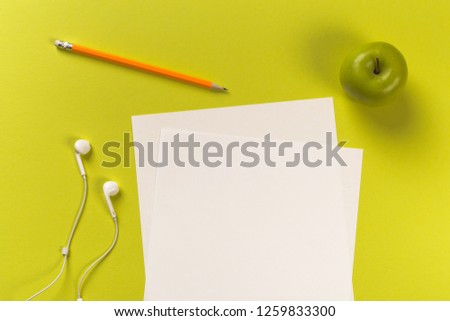 Pencils with white paper sheets on coloured backgroung, Office tool, white headphones and green apple