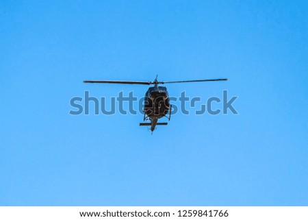The helicopter is flying in the blue sky. Aircraft Transportation. Military helicopter flying in the blue sky.
