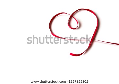 Isolated red satin ribbon with shape heart on white background. Concept of love, celebration, care, health, life