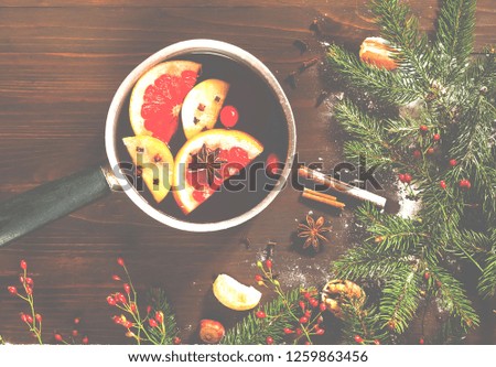 Christmas background. Hot mulled wine with ingredients in authentic ladle on wooden background. The concept of celebration and cooking warming drinks.Top view, close up, copy space