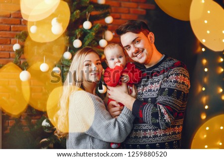 Beautiful family standing near Christmas tree. Cute mother in a gray sweater. Little boy with handsome father