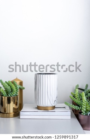 White Ceramic paint in natural marble patten setting on minimal books and surrounded with gold and copper pots with artificial plants inside / object / cozy interior concept / scene setting