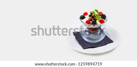 berry and icecream dessert in a clear glass bowl on a white plate on a white background