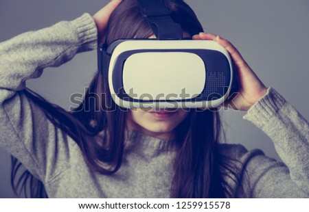 VR game player. Portrait of young gamer girl wearing vr headset for playing virtual reality games on smart phone device in studio. Enjoy modern virtual reality technology