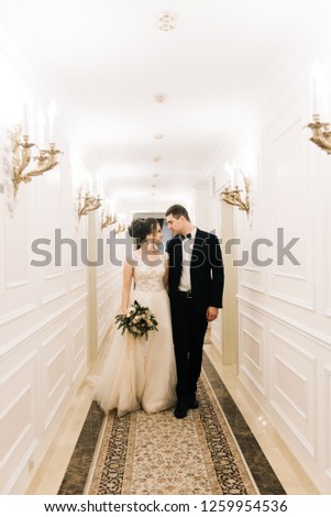 Happy young and loving bride and groom walk down the corridor of a luxury hotel. Wedding day