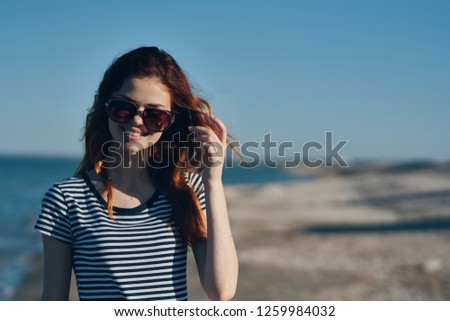 A woman in glasses and a striped T-shirt near the sea in nature                       