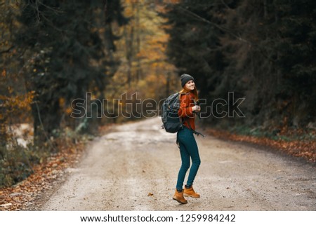 woman in a sweater with a backpack on the nature goes on the road                 
