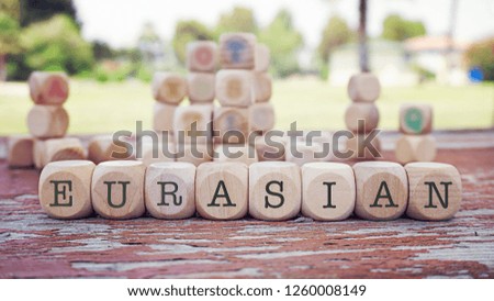 Eurasian word written on cube shape wooden blocks on wooden table.