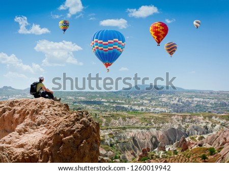 Amazing view with sport sitting girl and a lot of hot air balloons.  National park Anatolia, Cappadocia, Turkey. Artistic picture. Beauty world. The feeling of complete freedom.