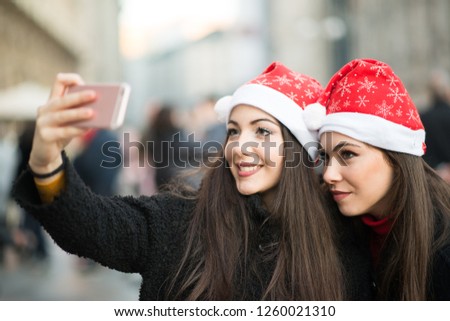 Smiling young women in Christmas hat taking a picture together