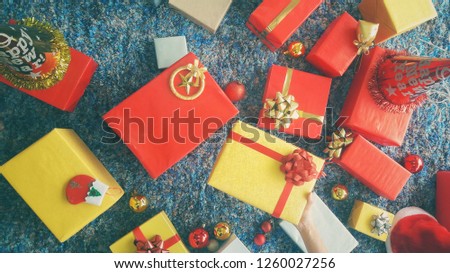 Holiday or celebrate Concept. Beautiful female hands holding Christmas present wrapped in kraft paper with set of colorful Christmas gifts lying on a retro navy blue carpet background. Vintage style.