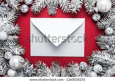 Merry Christmas and Happy Holidays greeting card, frame, banner. New Year. Noel. Silver, white and red Christmas ornaments and fir tree on red background top view. Winter holiday xmas theme. Envelope.