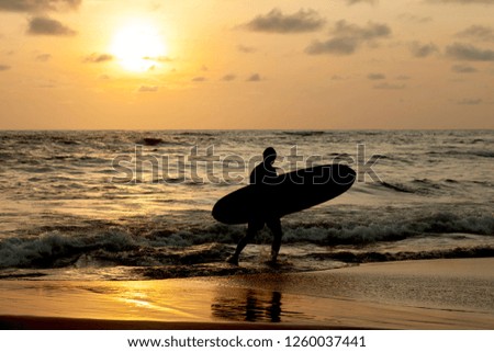 Silhouette Surfer out of the ocean at sunset