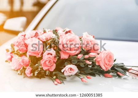 Beautiful wedding bouquet of roses on the hood of a car