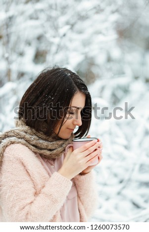 girl with a pink cup of coffee in the winter forest