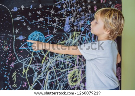 Little boy pointing space, planets and stars on the wall