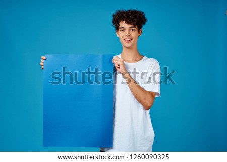 The man holds in his hand a blue poster                               