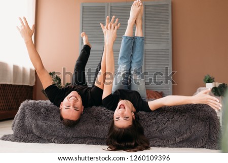 Boy and girl raise their legs up lying on a bed in a cosy room