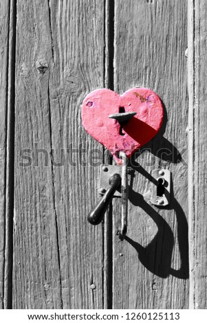 Old wooden door with heart shape lock keyhole and handle. Retro toned black white red photo. Open you heart concept. Love, mercy, charity idea. Vintage background.