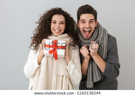 Image of european man and woman rejoicing while standing with present box isolated over gray background