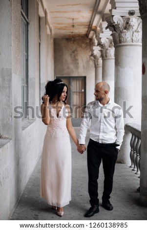 Charming young wedding couple walks along the corridor in an old building