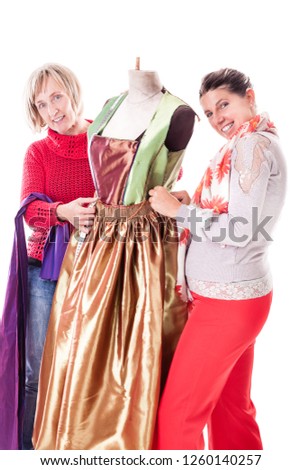 two happy seamstresses working on a dress on a mannequin isolated over a white background Royalty-Free Stock Photo #1260140257