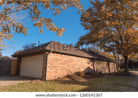 Rear garage and backyard with wooden fence of corner single-family house surround colorful fall foliage. Sunny autumn day in Flower Mound, Texas, USA