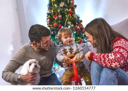 We love to play together. Happy family in room decorated for Christmas. Young father and mother playing with son. Christmas Family. Happiness. 