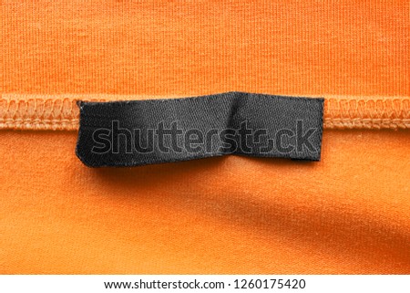 Blank black clothes label on yellow textile background