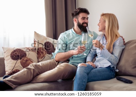 Picture of smiling  young couple at home ,they are drinking wine.