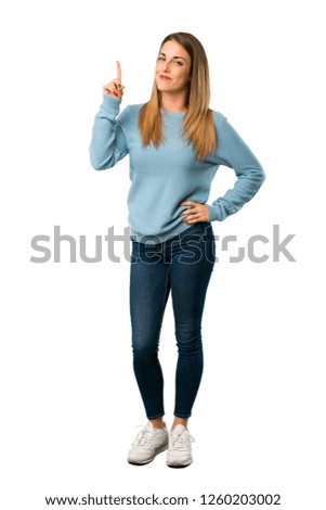 Full body of Blonde woman with blue shirt showing and lifting a finger in sign of the best on white background