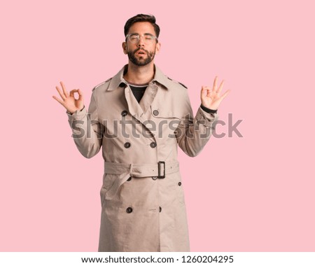 Young man wearing trench coat performing yoga