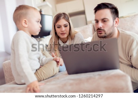 Beautiful young parents and their son watching movie.