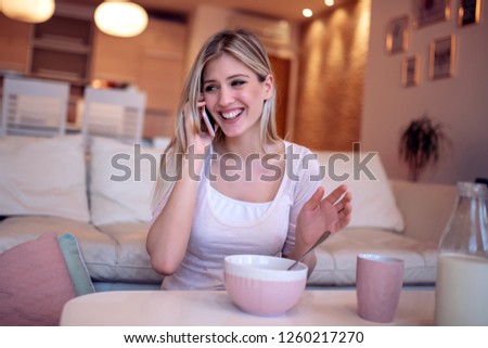 Portrait of beautiful woman talking on a mobile phone while having breakfast.