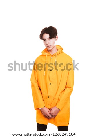 portrait of a teen guy in a yellow raincoat brunette in the studio.