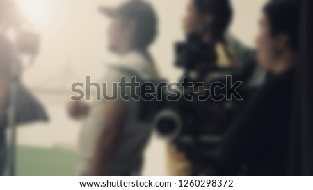 Blurred images of behind the scenes of filming or movie shooting or video production for online commercial and crew teams setting up light and prop and blue screen for next shot of camera recording